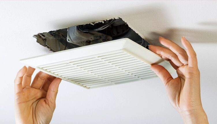 Male reaching up to open filter holder for air conditioning filter in ceiling